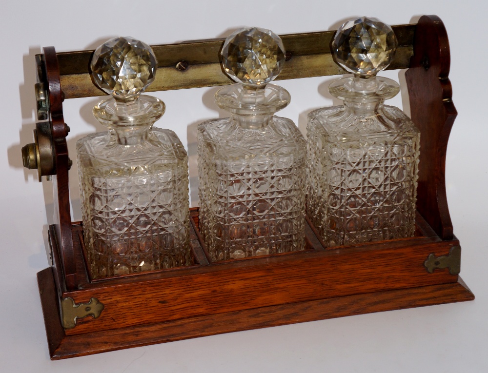 An oak three bottle tantalus with silver plated mounts, each decanter hobnail cut, 34cm wide, - Image 2 of 2