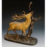 A gilt bronze and patinated model of a stag, eating leaves from a branch, 23cm wide, 26cm high,