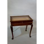 A mahogany bijouterie table, the hinged glazed top with outset angles,