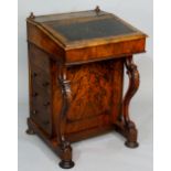 A Victorian walnut Davenport the sloping top with writing surface enclosing a fitted interior of