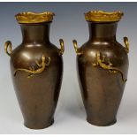 A pair of bronzed white metal two handled baluster vases each applied with a gilt lizard,