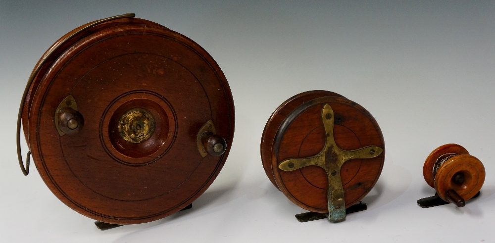 A large mahogany and brass fishing reel with pair of turned wood brass handles,