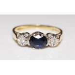 A diamond and sapphire ring the oval claw set sapphire flanked by two illusion set small diamonds,