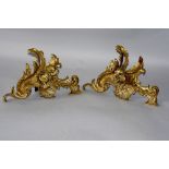 A pair of bronze Chenets in Rococo style with applied cast beasts amidst leafy scrolls, 30cm wide,
