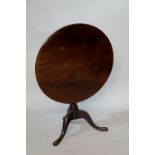 A George III mahogany tripod table the circular top above a vasular turned column,