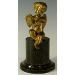 A brass winged cherub seated on a marble pedestal 15cm high,