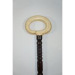 An unusual hardwood walking stick, turned overall and with ivory loop handle, ivory ferule,