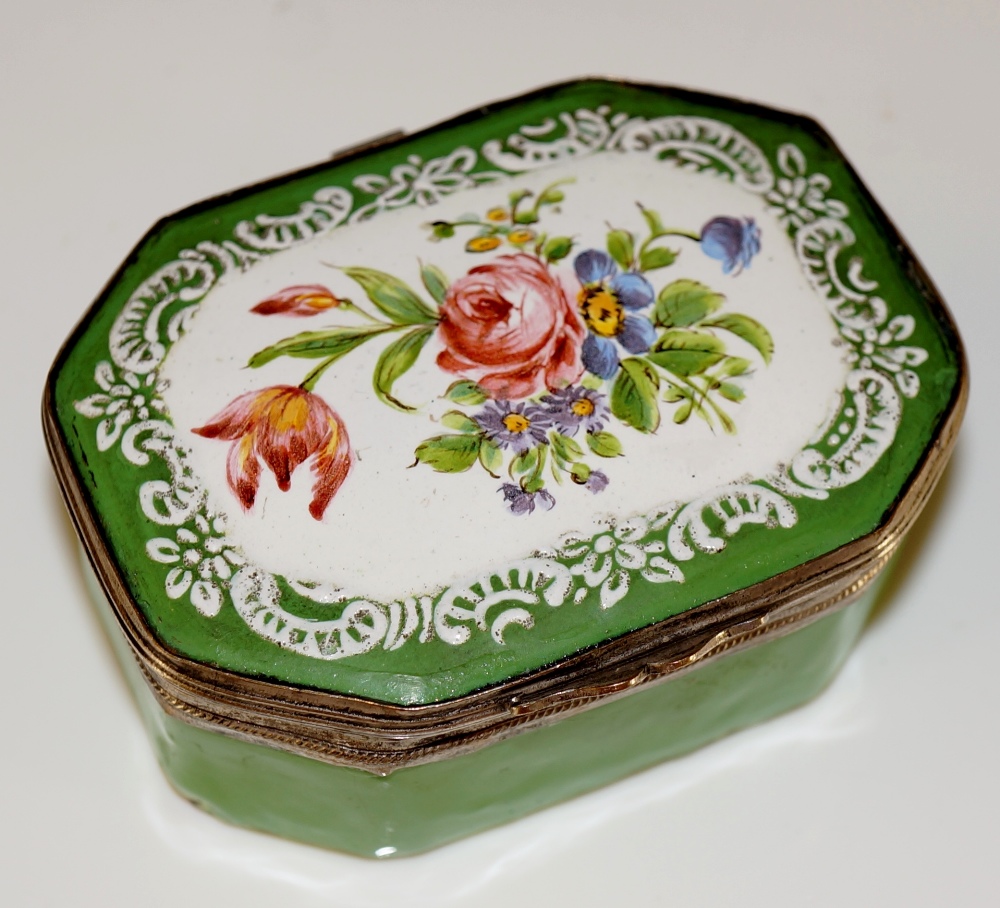 A 19th Century enamel pill box the hinged cover painted with a floral spray within a white enamel