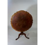 A George III mahogany tripod occasional table the shaped top inset with later tooled Morocco