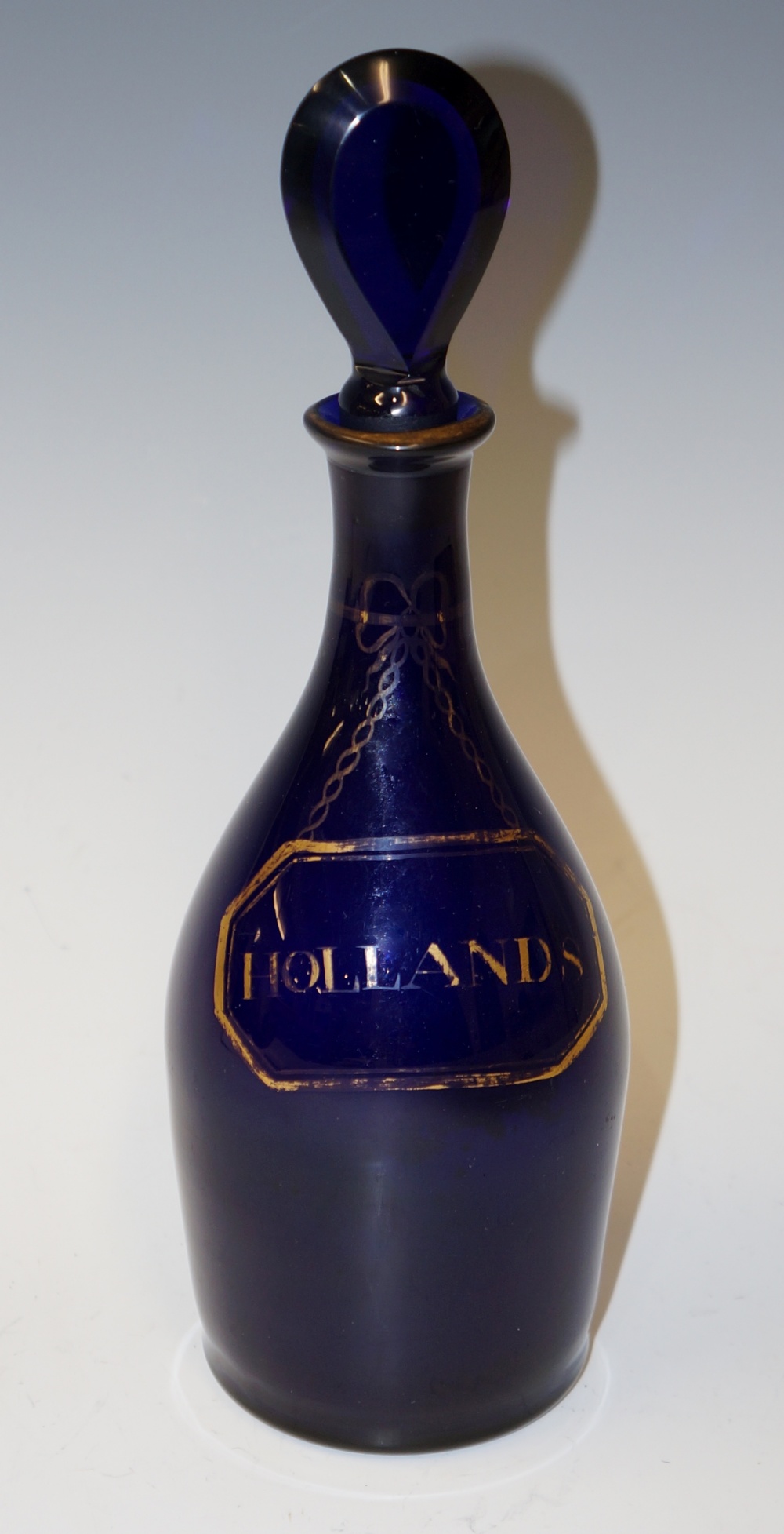 A Regency blue glass mallet shaped decanter and stopper the body detailed in gilt with a faux label