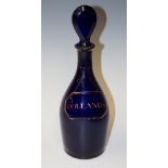 A Regency blue glass mallet shaped decanter and stopper the body detailed in gilt with a faux label