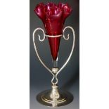 An early 20th Century cranberry glass flute with frilled rim on Art Nouveau scrolling silver plated