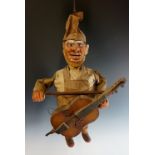 A European pottery puppet figure as a bearded cellist, painted decoration and fabric clothes,