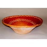 A large terracotta slip-ware decorated shallow bowl,