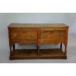 An oak dresser base the rectangular top above a frieze fitted two drawers, shaped apron,