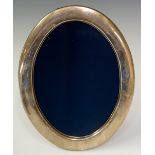 A plain oval silver photograph frame, 22.5cm high, 17.5cm wide, by R.G.