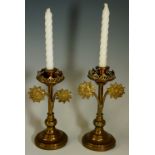 A set of two matching brass candlesticks, each set with two arching daisies,