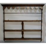 An oak plate rack in George III style the flared cornice with dentil moulded border and shaped