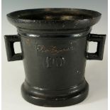 A cast iron mortar of conventional style with angular pierced handles the front inscribed and