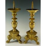 A pair of early 18th Century brass pricket candlesticks with bold baluster stems on triangular