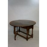 An oak gateleg table in late 17th Century style the oval top above a frieze drawer on bobbin turned