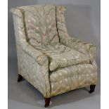 An Edwardian armchair with swept arms on mahogany square tapered legs fitted brass sockets and