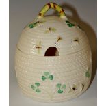 A Belleek basket moulded honey pot and cover detailed with three leaf clover and bees, 12cm high,