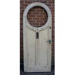 An Edwardian arched pine front door with circular aperture for leaded glass, letter box,