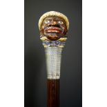 A walking stick with carved and stained ivory Blackamoor head wearing straw hat, blue bow tie,