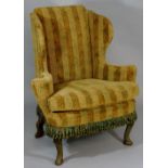 A George II style wingback armchair on green painted scroll carved cabriole legs, 112cm high max.