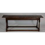 A 17th Century style oak enclosed long stool the hinged top above plain frieze,