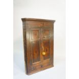 A George III oak hanging corner cupboard with cavetto moulded cornice above a frieze with