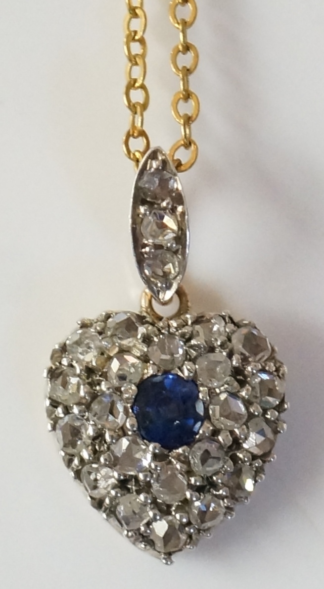 A diamond set heart shaped pendant with central sapphire brilliant,