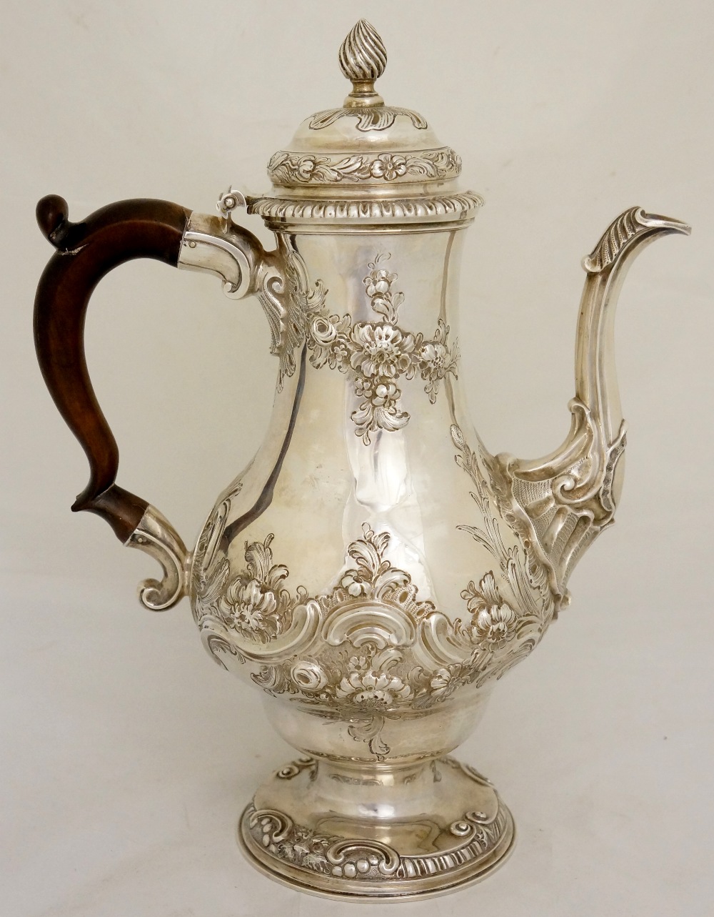 A George II pear-shaped coffee pot, the hinged lid with wrythen fluted finial, above a body chased