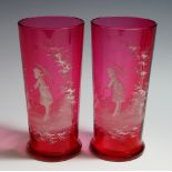 A pair of cranberry glass beakers with white enamelled scene of a young girl under a parasol in