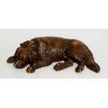 Black Forest - a finely carved dog lying down, its head between its paws, glass eyes, 30cm wide,