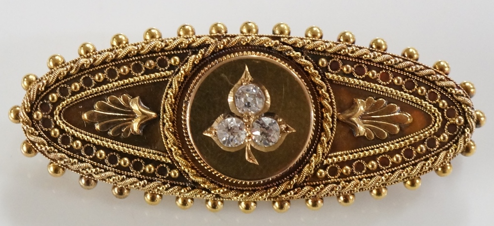 A Victorian 15 carat gold brooch the oval frame with raised circular centre set three diamond