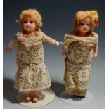 A pair of wax headed dolls, each with fixed blue eyes, painted detailing to faces,