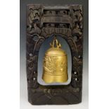 A Chinese brass table bell contained within a wire inlaid ebonised hardwood frame,