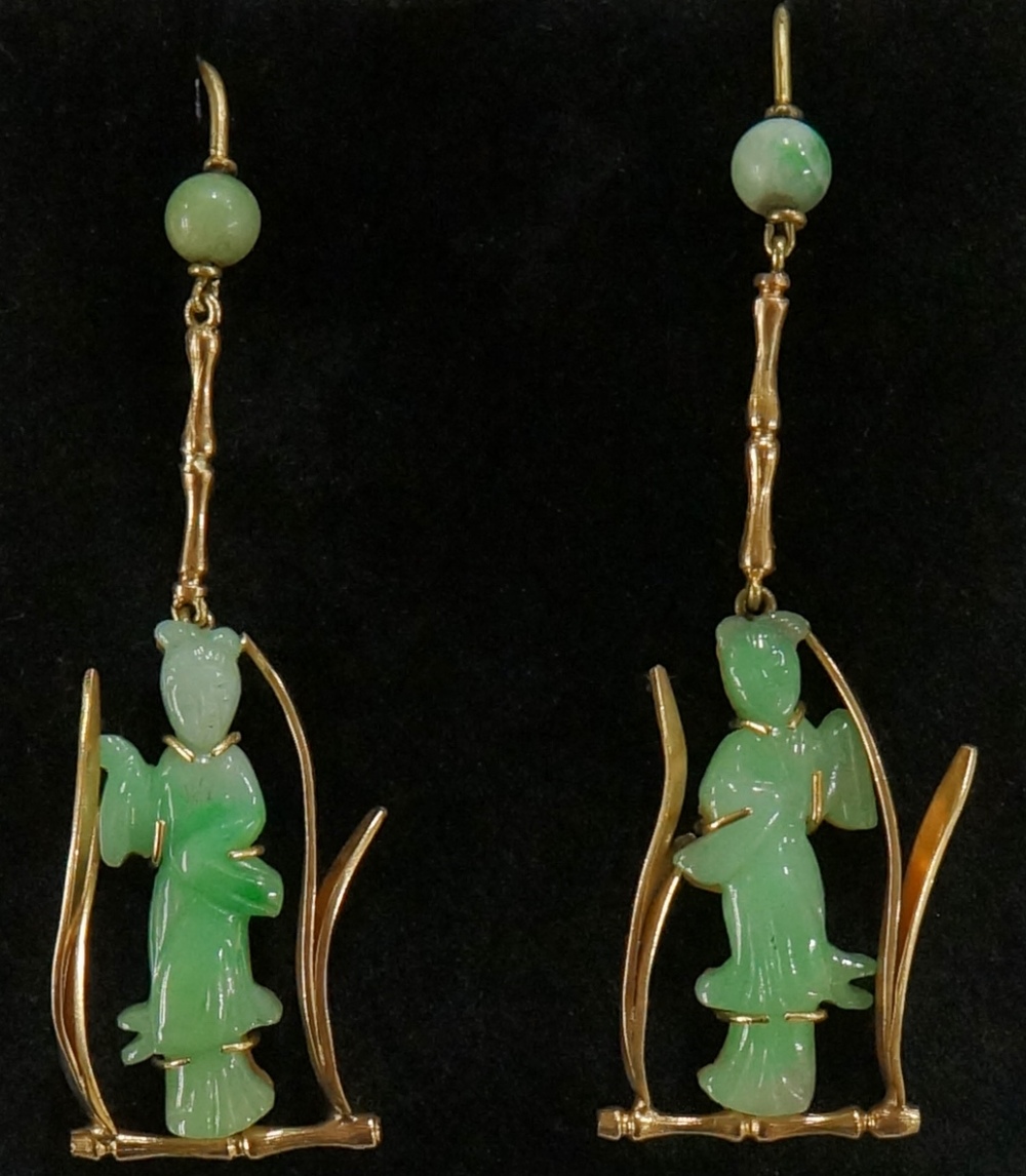 A pair of jadeite and gold earrings carved with female figures within stylised leafy frame,