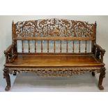 A Chinese hardwood sofa the back with a finely pierced and carved panel of dragons chasing the