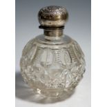 A cut glass spherical scent bottle with silver collar, the lid embossed with scrolls and foliage,