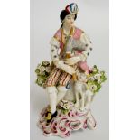 A porcelain figure of a bagpiper with dog at his feet, floral bocage behind,