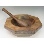 An octagonal walnut mortar with circular dished centre, 31cm wide; together with a pestle,