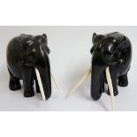 A large pair of lignum carved elephants with long ivory tusks, 21cm high, 26cm long overall,