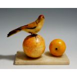 A carved and stained alabaster group with a bird perched on top of a peach beside an apricot,