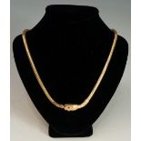 A French gold snake necklace of articulated design with engraved neck the head with garnet eyes and