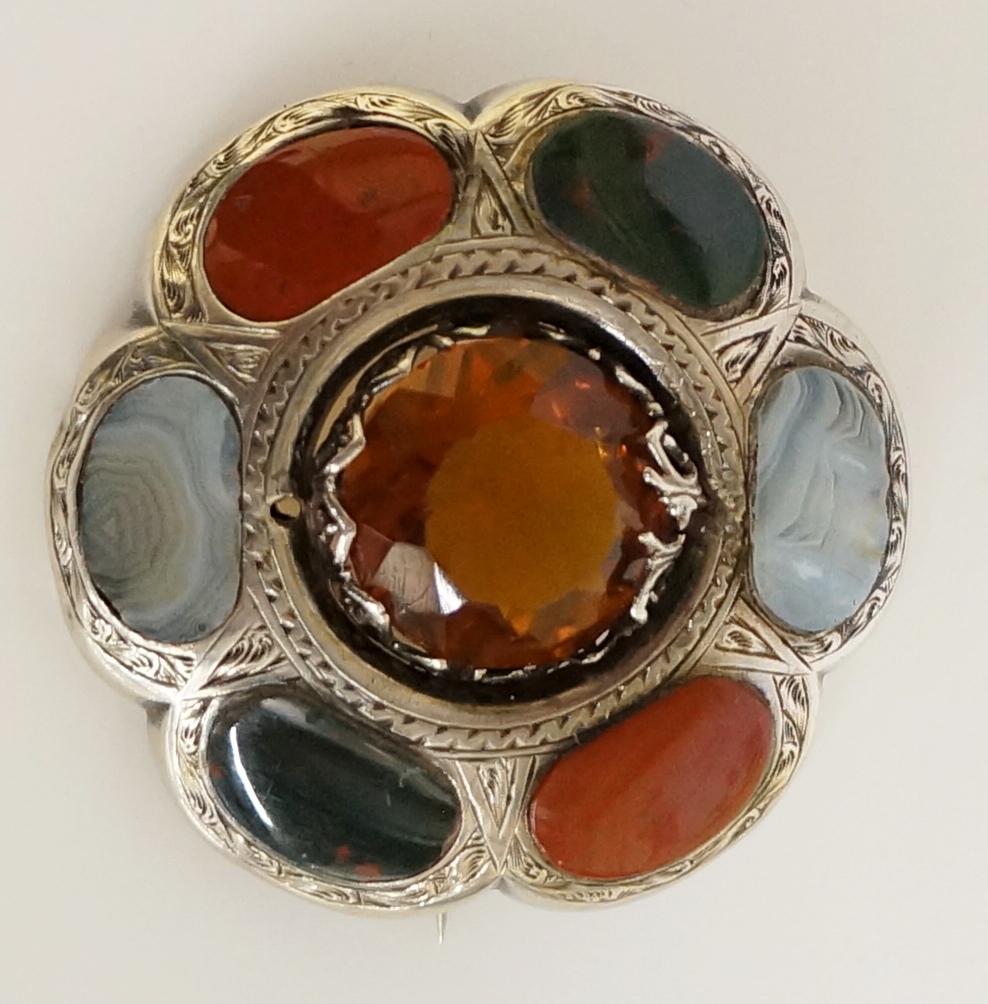 A Scottish hardstone brooch of flower head design with central yellow stone facet cut within an