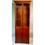 A George IV mahogany gun cabinet with flared cornice enclosed by a pair of glazed and panelled