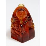 An amber coloured resin seal carved with a figure and ducks, a receptacle on his back,